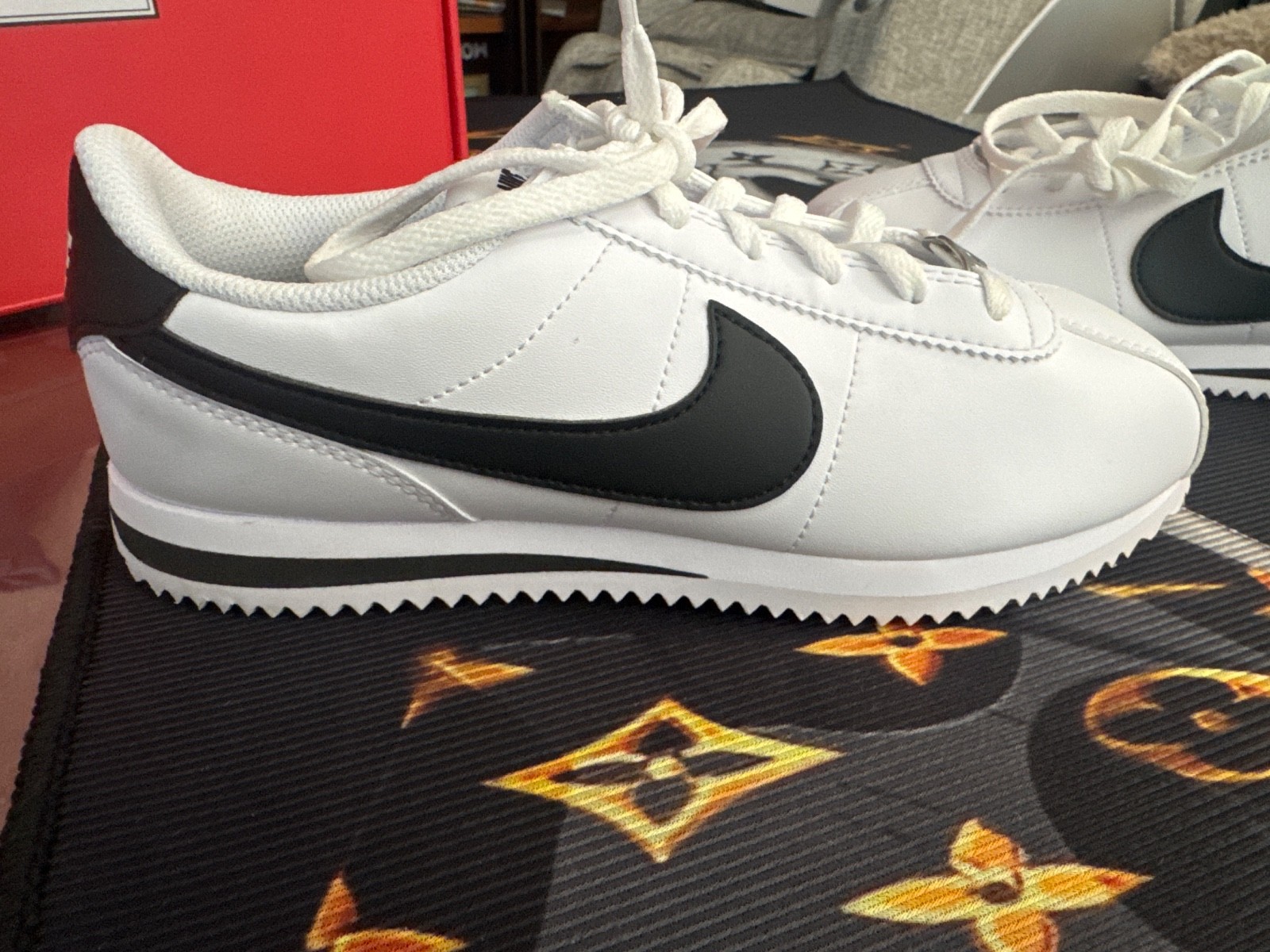 Nike Cortez sneakers featuring a smooth white upper and a distinct black Swoosh 