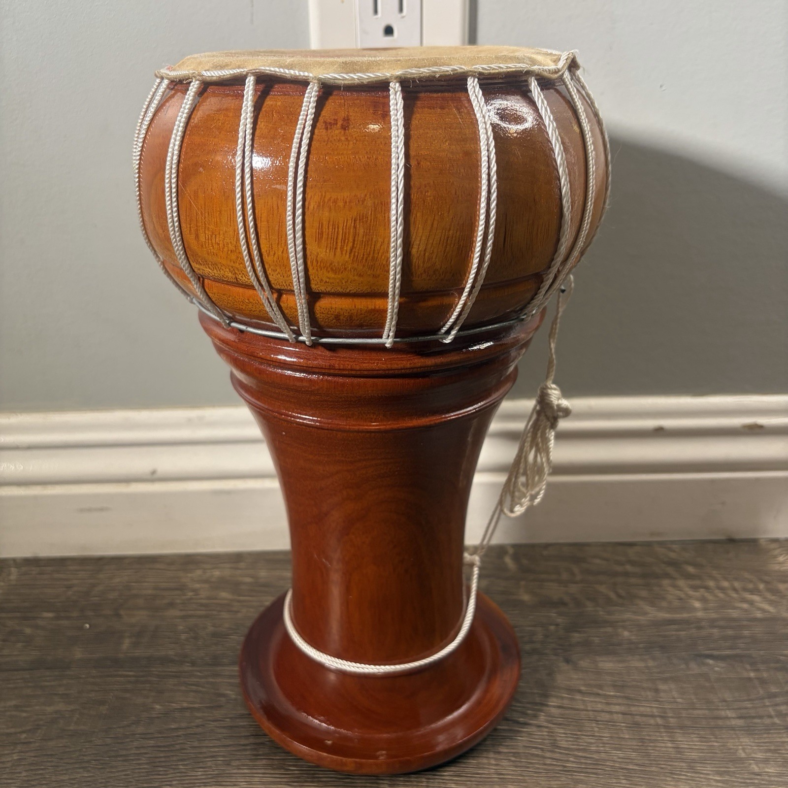 Vintage wooden djembe hand drum with natural skin head and rope tuning.