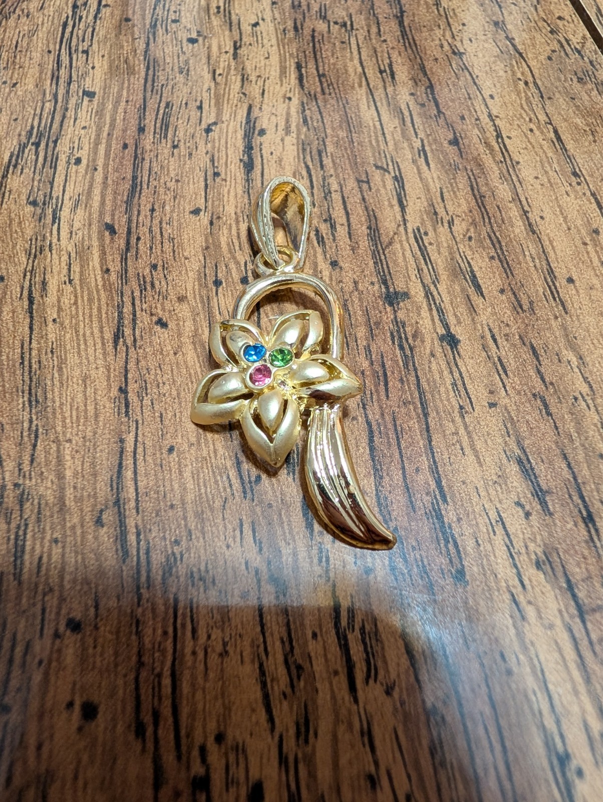 New gold toned pendant with rhinestone in the flower. 