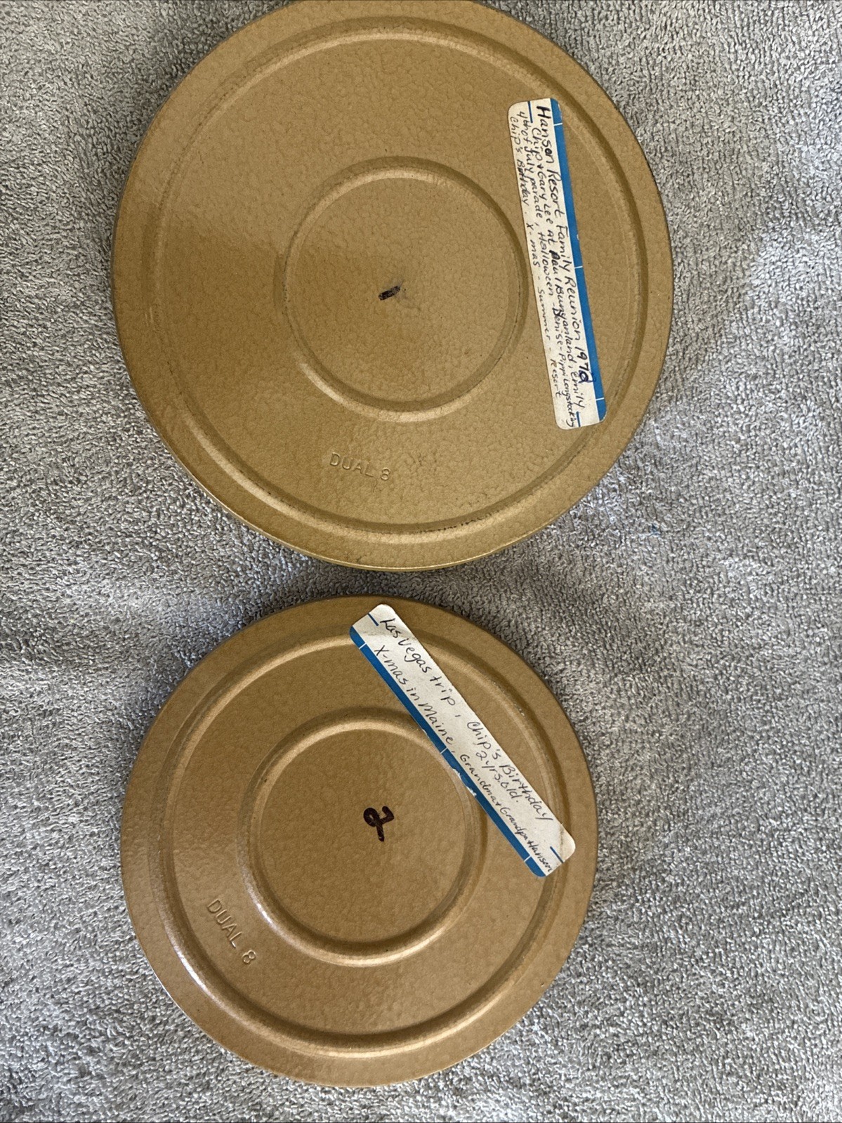 two vintage DUAL 8 mm film reels in their protective storage cans, labeled