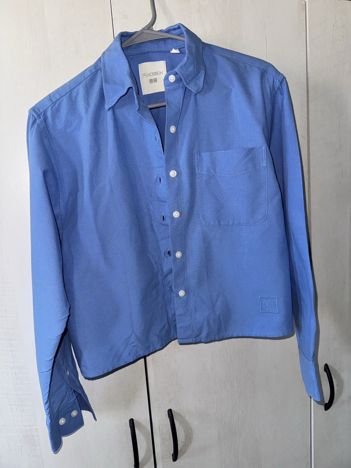 Blue long-sleeve button-up shirt from the JW Anderson x Uniqlo collaboration. Blue long-sleeve button-up shirt from the JW Anderson x Uniqlo collaboration.