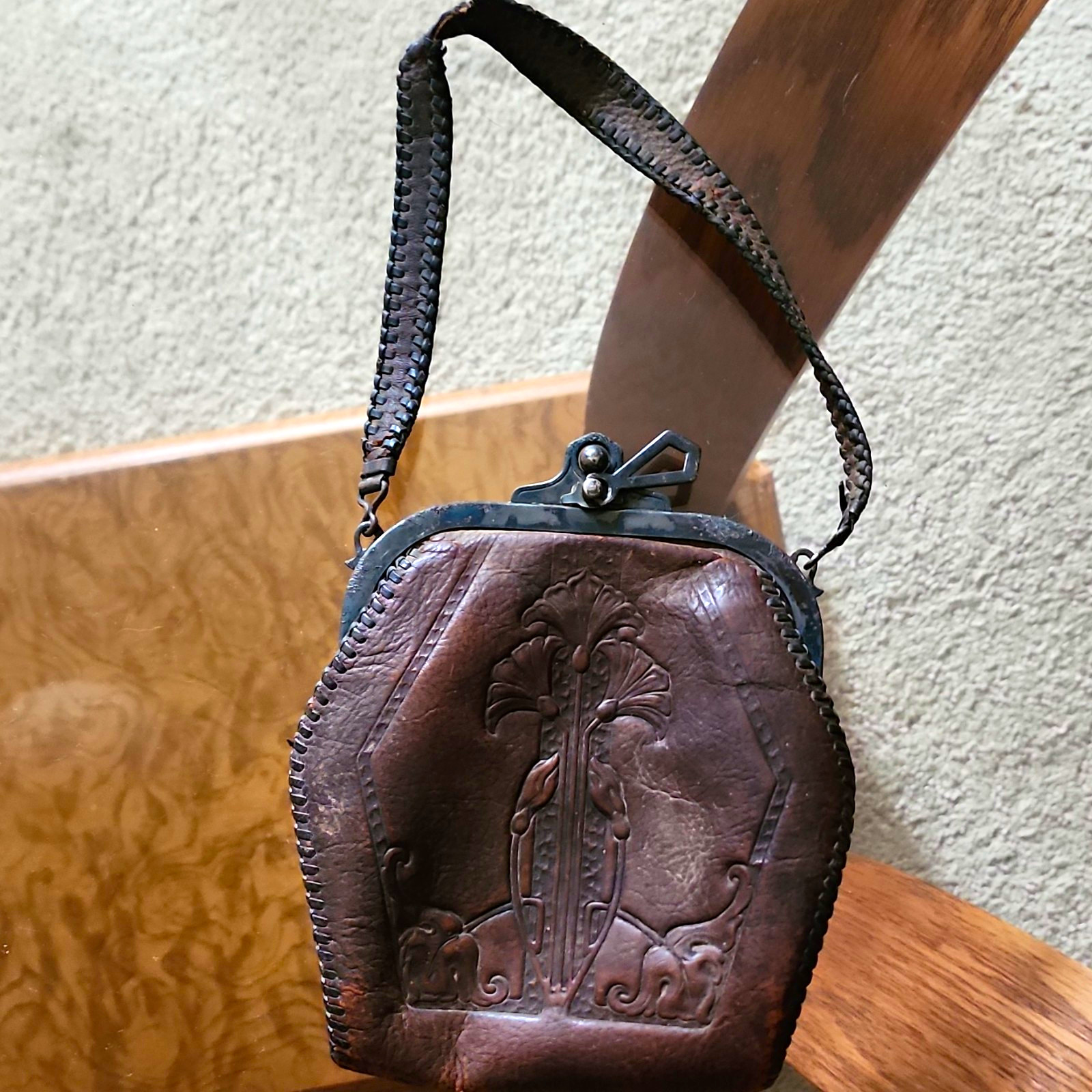 vintage brown leather handbag featuring an ornate hand-tooled floral design